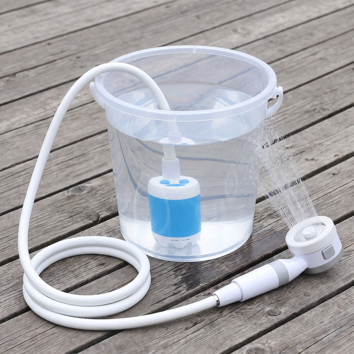 Het pompje ligt in de emmer, de slang uitgerold naar de douchekop